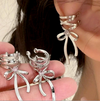 Close-up of a woman wearing a silver bow dangle cuff earring, featuring a lace-up cuff design and sparkling rhinestone accent, with an elegant, modern style.