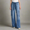 Close-up of high-waisted blue denim palazzo jeans with utility-style cargo pockets and a matching denim tie belt, styled with a white tank and cream heels