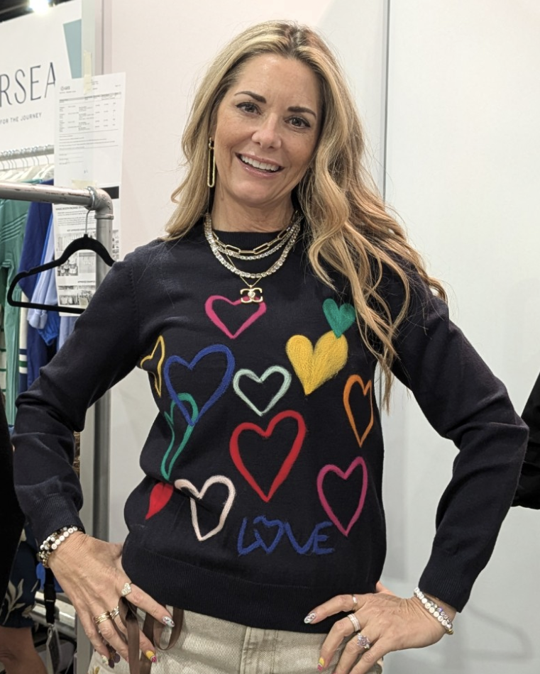 A black knit sweater featuring multicolored embroidered hearts in red, yellow, blue, green, and pink, designed for a fun and playful look.