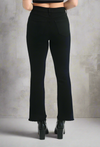 Back view of black demi bootcut jeans with frayed hems, styled with black platform ankle boots and a crop top