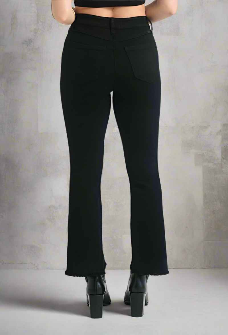 Back view of black demi bootcut jeans with frayed hems, styled with black platform ankle boots and a crop top
