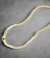 Close-up of gold Cuban chain necklace with large round simulated diamonds and padlock clasp on model's neck