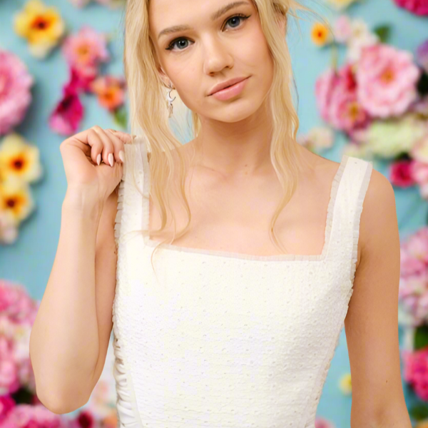 White eyelet corset-style crop top with a square neckline and ruched side detailing, styled with high-waisted denim for a fresh, feminine look.

