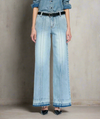 Woman wearing light blue wide-leg jeans with double front seam stitching, raw hems, and a black belt