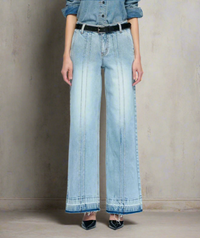 Woman wearing light blue wide-leg jeans with double front seam stitching, raw hems, and a black belt