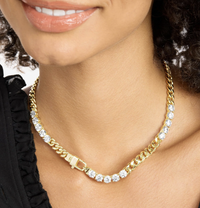 Close-up of gold Cuban chain necklace with large round simulated diamonds and padlock clasp on model's neck