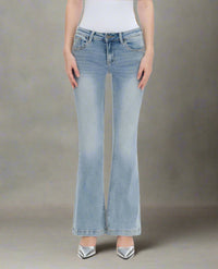 Woman wearing low-rise light wash mini flare jeans with a finished hem and natural fade, paired with silver heels
