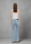 Back view of light wash low-rise flare jeans with finished hems, styled with a white tank top and heels