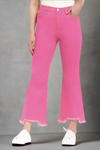 Woman wearing hot pink high-rise bootcut jeans with frayed shark bite hems, paired with white sneakers and tank