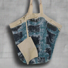 Reversible slouchy canvas tote bag made from recycled coffee bean bags, featuring a fuzzy navy plaid interior, oversized grommets, adjustable drawstring closure, and webbing strap handles. Includes a small zip-up pouch.