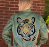 An army-green bomber jacket with a sparkling rhinestone tiger design on the back, featuring a bold orange interior lining and zippered pocket details.
