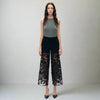 Woman wearing high-rise black sparkle jeans with lace cutout panels and rhinestones, styled with heels and a grey top