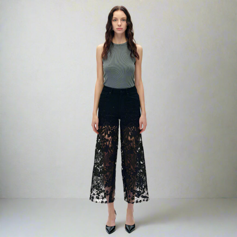 Woman wearing high-rise black sparkle jeans with lace cutout panels and rhinestones, styled with heels and a grey top