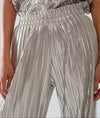 Front view close-up of metallic silver pleated pants with wide elastic waistband and soft drape