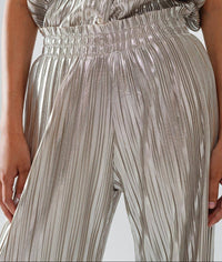 Front view close-up of metallic silver pleated pants with wide elastic waistband and soft drape