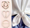 A heart-shaped t-shirt tie clip with pearl details, used to create a cinched knot effect on tops and blouses for a stylish touch.