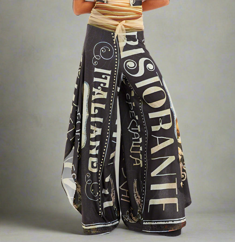 Black wide-leg pants with vintage Italian restaurant text print and rhinestone embellishments, styled with neutral wrap top