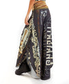 Black wide-leg pants with vintage Italian restaurant text print and rhinestone embellishments, styled with neutral wrap top