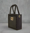 Mini black jelly handbag with studded edges and a gold-tone “V” buckle on the front, featuring textured top handles and gold grommet detail.