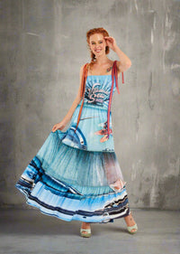 Woman wearing a convertible maxi dress with vibrant ocean print, tie straps, and rhinestone details; worn as a dress with peek-a-boo panel.