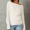 Model wearing a taupe waffle-knit slouchy sweater styled off one shoulder, paired with light denim jeans against a grey background.

