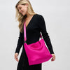 Model carrying a medium woven neoprene tote in a warm neutral tone, featuring a chic, textured design with sturdy woven handles.