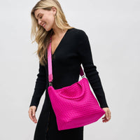Model carrying a medium woven neoprene tote in a warm neutral tone, featuring a chic, textured design with sturdy woven handles.