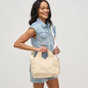 Model carrying a woven straw tote bag in a chic, summery design, featuring gold hardware and an adjustable strap, perfect for vacation and warm-weather styling.