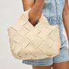 Model carrying a woven straw tote bag in a chic, summery design, featuring gold hardware and an adjustable strap, perfect for vacation and warm-weather styling.