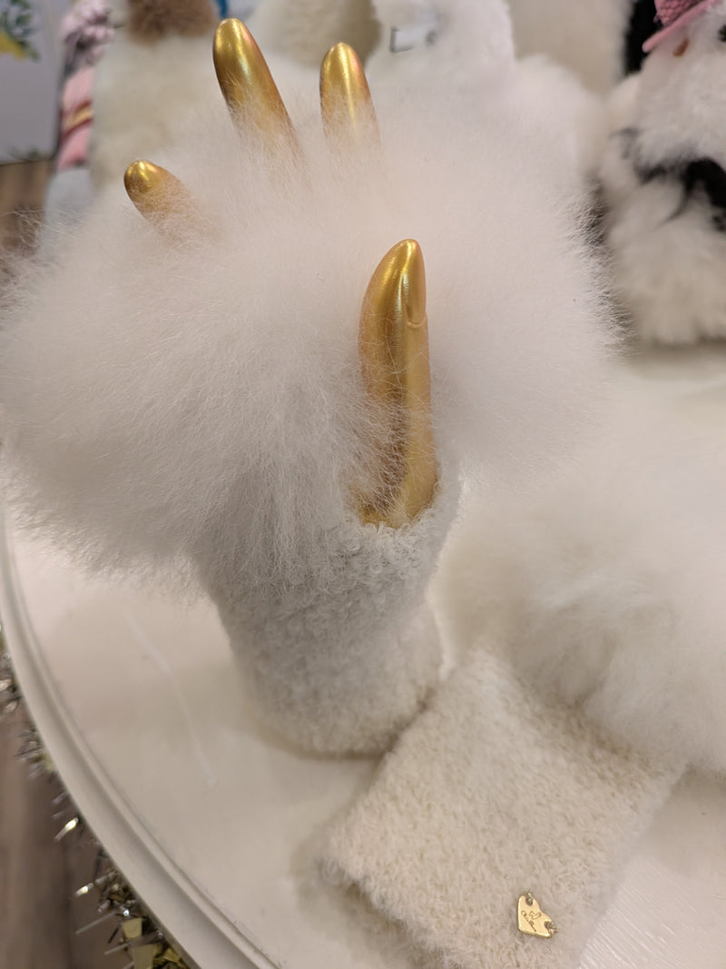 A pair of alpaca wool fingerless gloves with a fluffy fur trim, displayed on a boutique table.